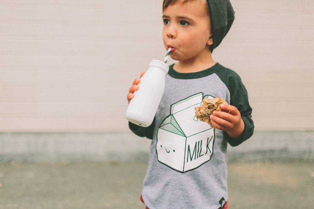 Gorgeous toddler baby boy drinking milk and cookies