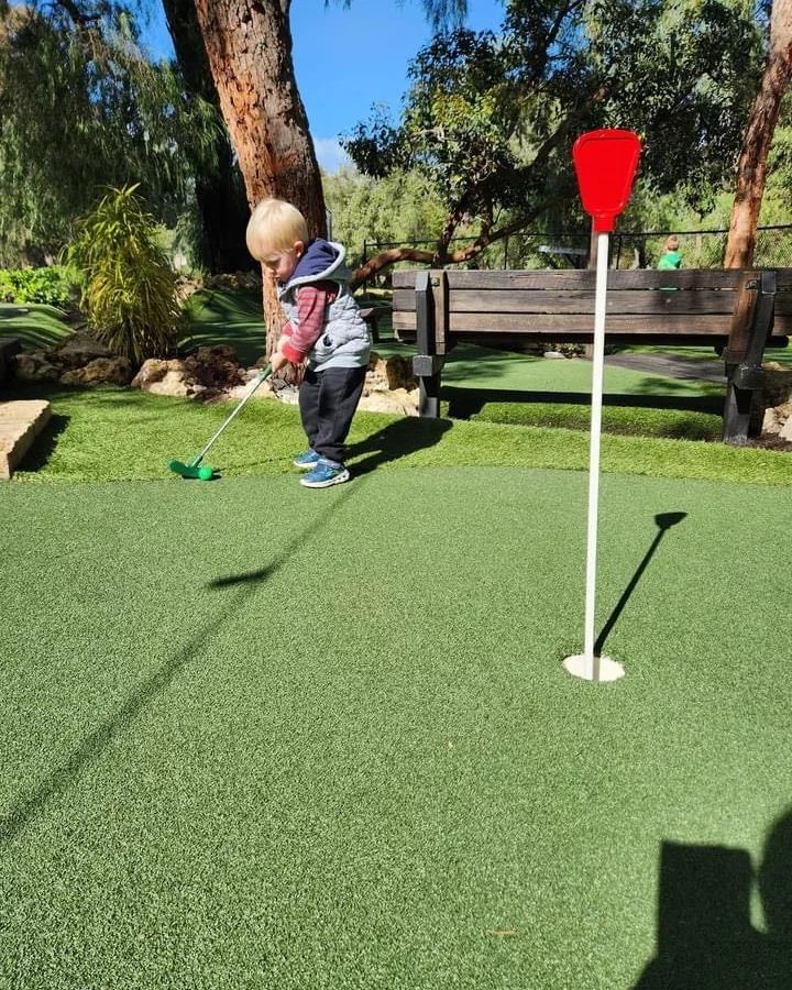 Toddler playing mini golf