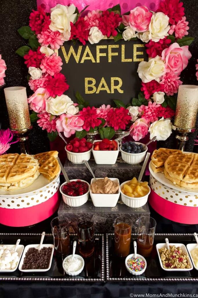 A waffle bar setup with waffles and assorted toppings like berries, whipped cream, and chocolate chips for a baby shower brunch.